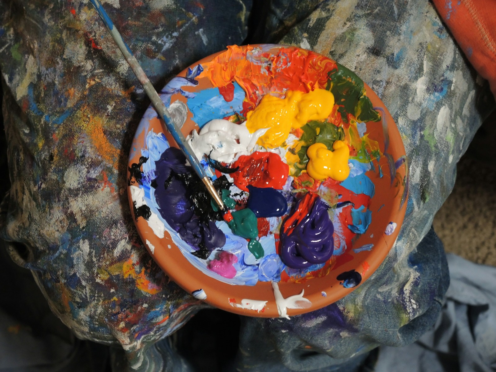 A painter's palette loaded with bright colors and a brush